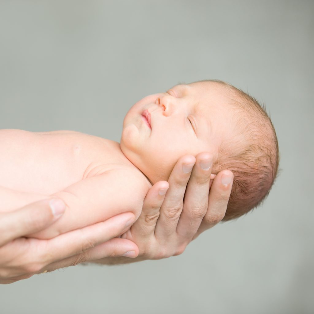 Portrait of a sleeping newborn held with hands